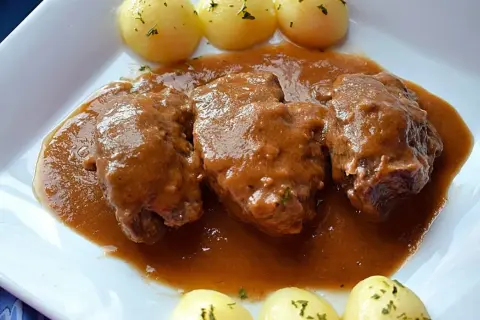 Carrilleras de ternera estofadas en salsa, acompañadas de patatas cocidas y espolvoreadas con perejil. Un plato casero y reconfortante.