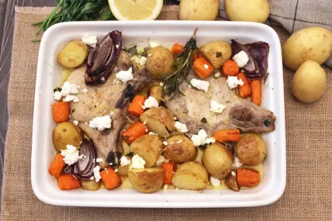 Chuletas de cerdo al horno con patatas, zanahorias, cebolla morada y queso feta. Un plato sabroso y completo.