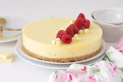 Tarta de chocolate blanco decorada con frambuesas frescas y trocitos de chocolate.