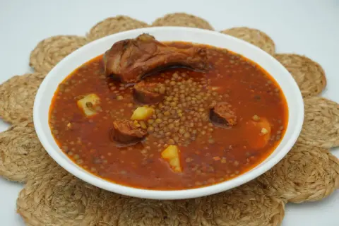 Un plato humeante de lentejas con chorizo, patatas y un muslo de pollo. Un manjar casero listo para disfrutar.