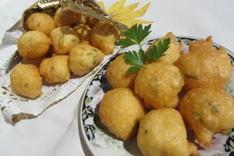 Buñuelos de bacalao hechos en Thermomix, dorados y crujientes, servidos en un plato y en un cono dorado.