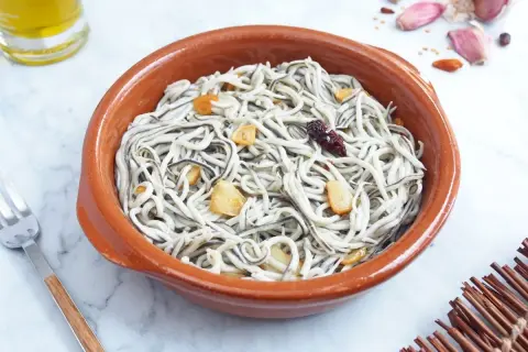 Deliciosas gulas al ajillo en cazuela de barro, con láminas de ajo dorado y un toque picante.