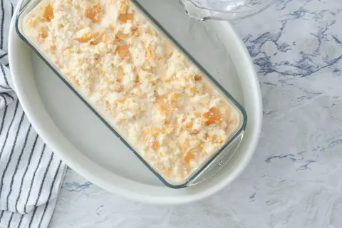 Preparando una deliciosa receta de pudin casero en un molde de vidrio, con trozos de galleta integrados.