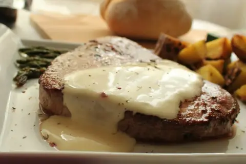Tierna ternera en salsa cremosa, acompañada de espárragos y patatas asadas. Un plato principal delicioso.