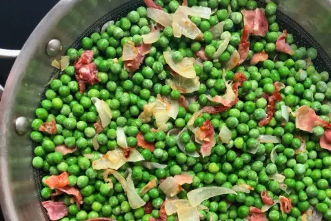 Guisantes con jamón y cebolla en una sartén. Un plato sencillo y sabroso, perfecto para acompañar.