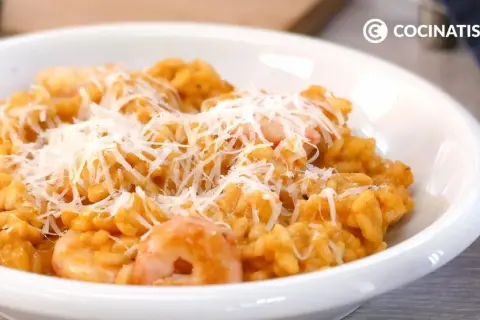 Un cremoso risotto de gambas, coronado con queso rallado, listo para disfrutar.