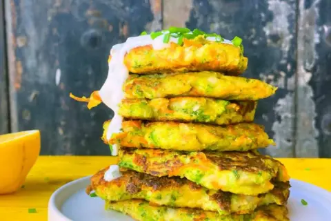 Torre de tortitas de brócoli y zanahoria, cubiertas con crema y cebollino.