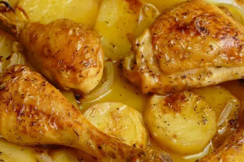Pollo al horno con patatas, dorado y jugoso, con hierbas aromáticas y cebolla. Un plato casero irresistible.