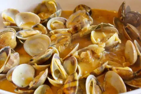 Un plato humeante de almejas a la marinera, con su salsa dorada y trozos de ajo. ¡Un manjar!