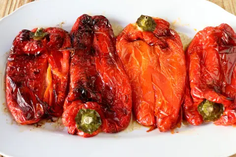 Pimientos rojos asados en freidora de aire, con piel arrugada y un brillo apetitoso.