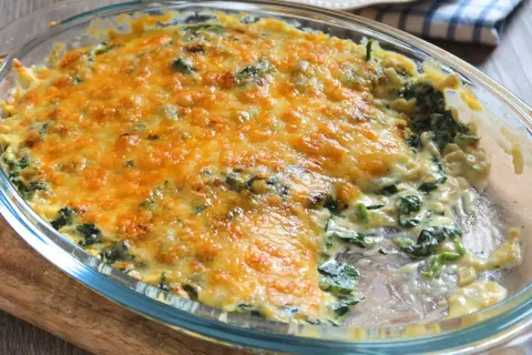 Delicioso plato de espinacas a la crema, gratinado con queso dorado y burbujeante, listo para servir.