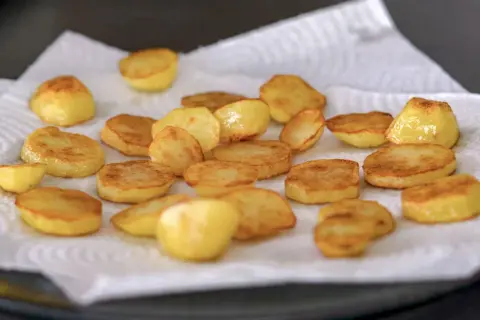 Patatas al horno doradas y crujientes, recién salidas del horno y reposando sobre papel absorbente. ¡Listas para disfrutar!