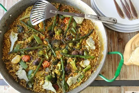Un delicioso arroz con verduras, lleno de brócoli, espárragos y alcachofas, listo para servir.
