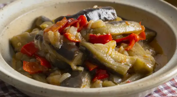 Berenjenas en escabeche, un plato casero con trozos de berenjena, pimientos rojos y cebolla en una salsa sabrosa.