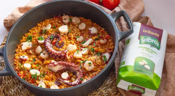 Delicioso arroz con pulpo y gambas en paellera, listo para disfrutar.