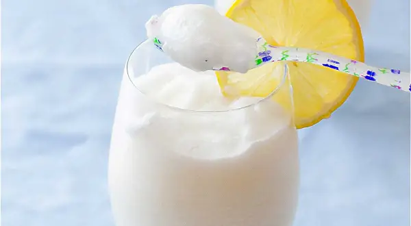 Refrescante sorbete de limón al cava, servido en copa con rodaja de limón y cuchara decorada.