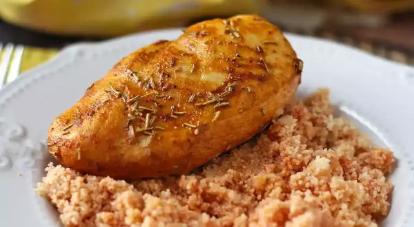 Pechuga de pollo dorada y jugosa, cocinada en freidora de aire, servida sobre una cama de cuscús.
