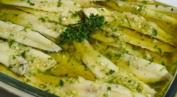 Boquerones en vinagre, frescos y listos para disfrutar, con ajo picado y perejil en aceite de oliva.