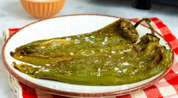 Pimientos verdes asados en freidora de aire, servidos en plato blanco con sal gruesa.
