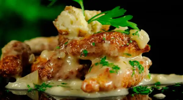 Deliciosas albóndigas de rape doradas, cubiertas con una cremosa salsa y perejil fresco.