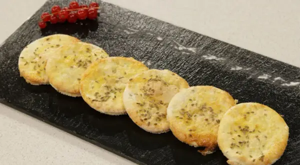 Deliciosas tortas de anís, doradas y crujientes, adornadas con semillas de anís y un toque de frutos rojos.