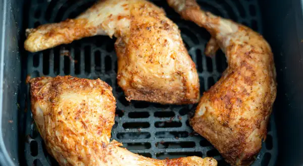 Muslos de pollo dorados y jugosos en la freidora de aire, listos para disfrutar.