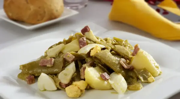 Deliciosa ensalada de judías verdes con trocitos de jamón y huevo duro, acompañada de patatas. Un plato casero y sabroso.