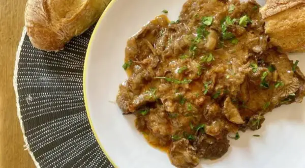 Delicioso fricando de ternera con trozos de pan crujiente, listo para disfrutar.