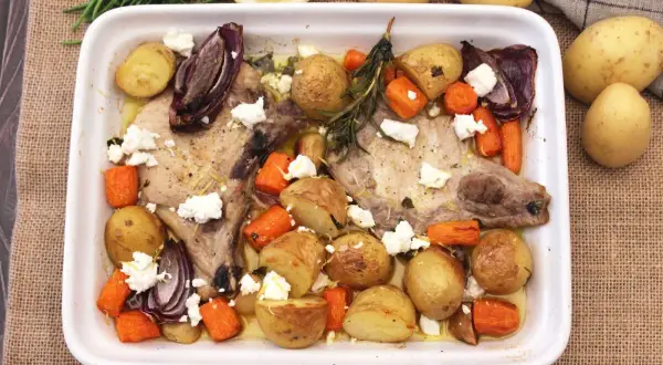 Chuletas de cerdo al horno con patatas, zanahorias, cebolla morada y queso feta. Un plato sabroso y completo.
