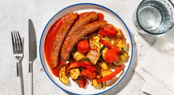 Salchichas con tomate y verduras asadas, un plato sabroso y saludable.