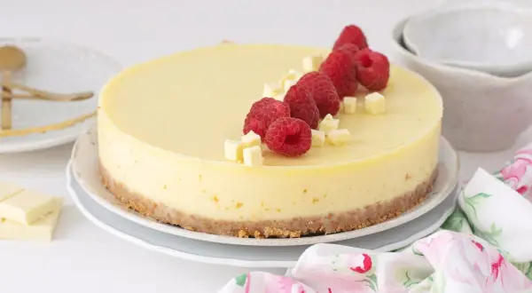 Tarta de chocolate blanco decorada con frambuesas frescas y trocitos de chocolate.