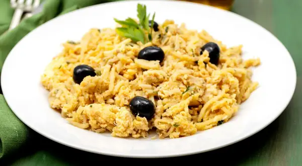 Delicioso bacalao a bras, un plato tradicional portugués con patatas finas, huevo y aceitunas negras, adornado con perejil fresco.