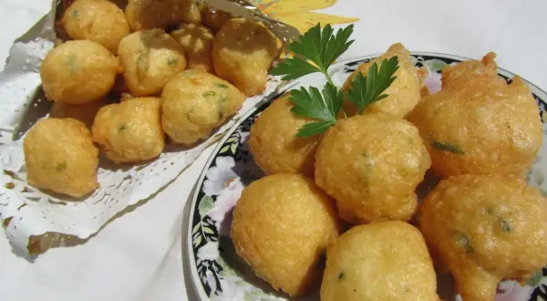 Buñuelos de bacalao hechos en Thermomix, dorados y crujientes, servidos en un plato y en un cono dorado.
