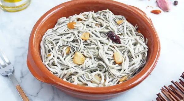 Deliciosas gulas al ajillo en cazuela de barro, con láminas de ajo dorado y un toque picante.