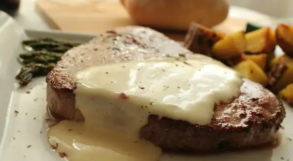 Tierna ternera en salsa cremosa, acompañada de espárragos y patatas asadas. Un plato principal delicioso.