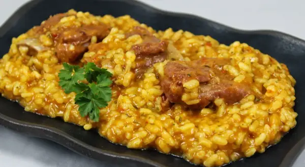 Arroz con costillas jugosas, preparado en Thermomix, servido en plato negro con perejil fresco.