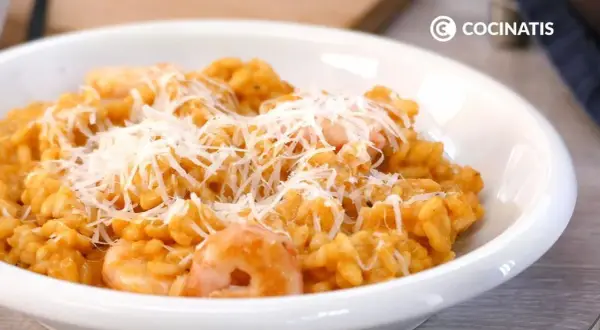 Un cremoso risotto de gambas, coronado con queso rallado, listo para disfrutar.