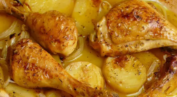 Pollo al horno con patatas, dorado y jugoso, con hierbas aromáticas y cebolla. Un plato casero irresistible.