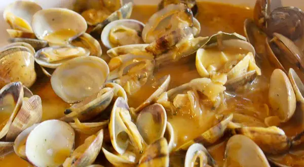Un plato humeante de almejas a la marinera, con su salsa dorada y trozos de ajo. ¡Un manjar!
