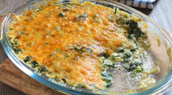 Delicioso plato de espinacas a la crema, gratinado con queso dorado y burbujeante, listo para servir.