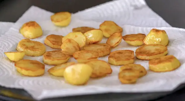 Patatas al horno doradas y crujientes, recién salidas del horno y reposando sobre papel absorbente. ¡Listas para disfrutar!