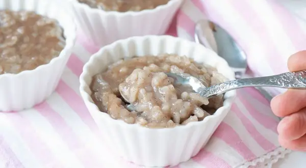 Delicioso arroz con leche de soja en cuencos blancos, con una cuchara lista para probar.
