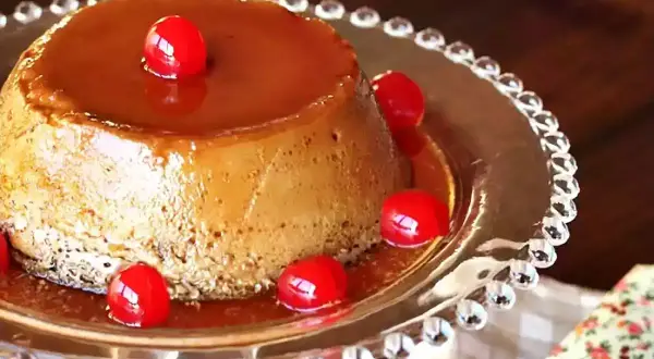 Delicioso flan de café con caramelo líquido y cerezas rojas, servido en un plato de cristal decorado.