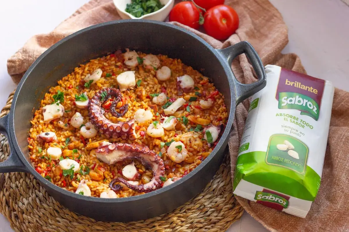 Delicioso arroz con pulpo y gambas en paellera, listo para disfrutar.