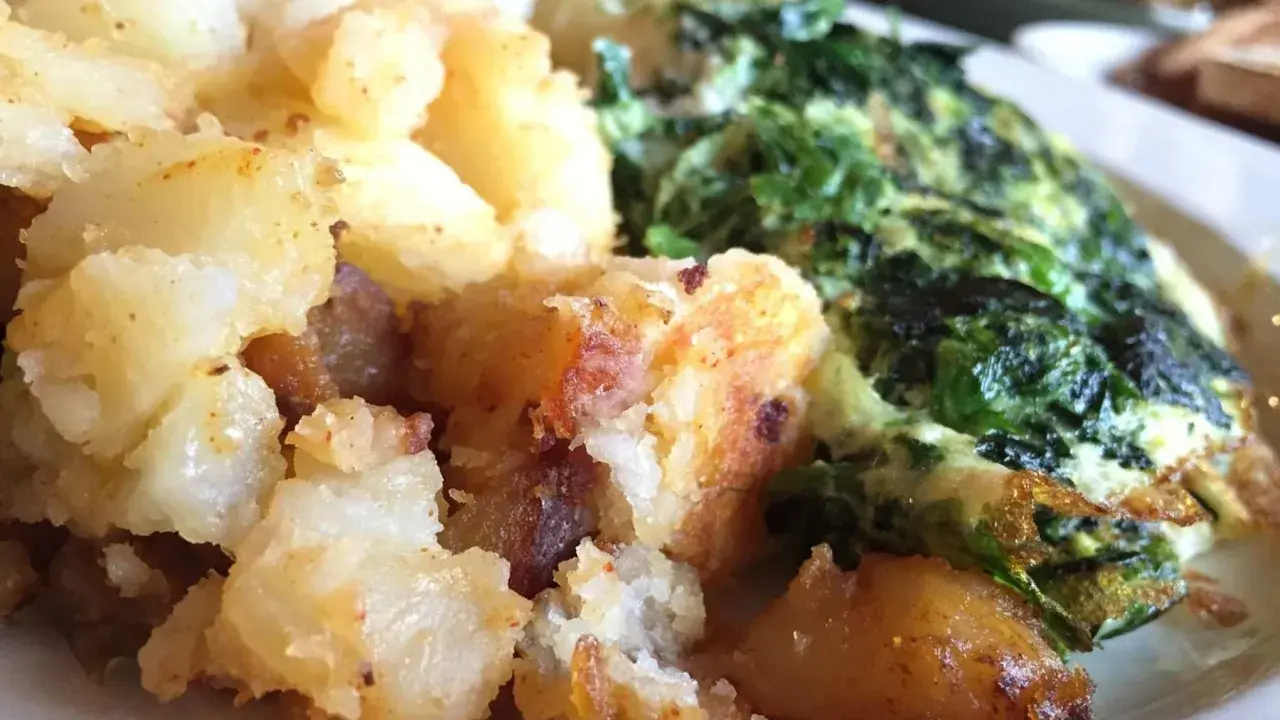 Patatas doradas y crujientes junto a unas espinacas con patatas, un plato casero y reconfortante.