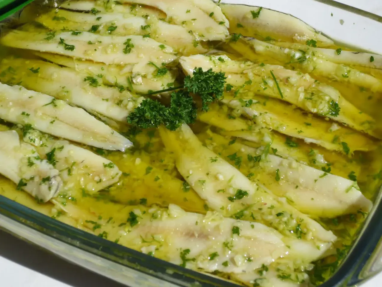 Boquerones en vinagre, frescos y listos para disfrutar, con ajo picado y perejil en aceite de oliva.