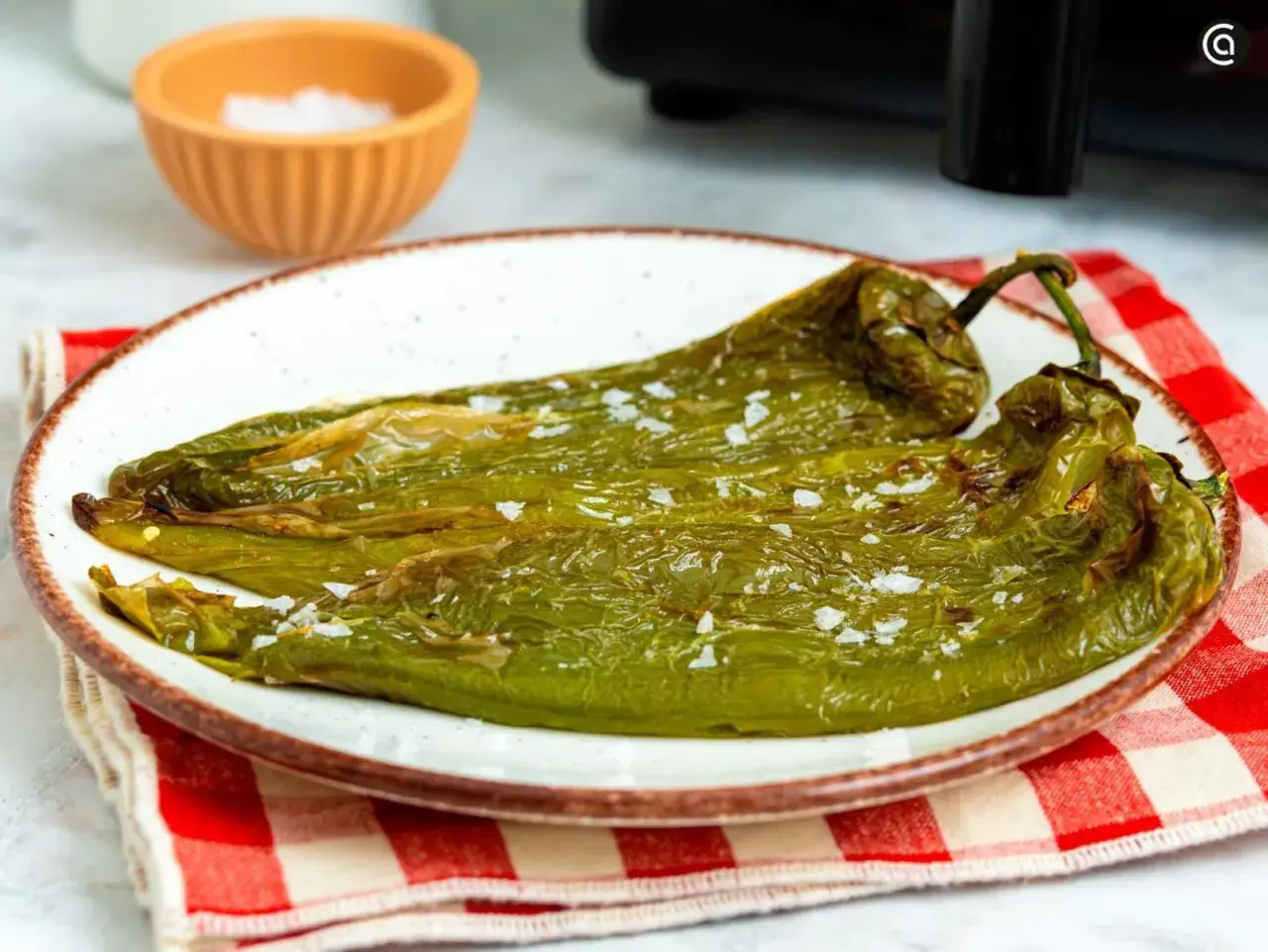 Pimientos verdes asados en freidora de aire, servidos en plato blanco con sal gruesa.