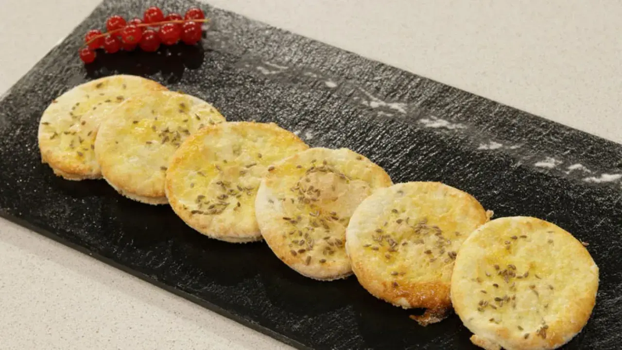 Deliciosas tortas de anís, doradas y crujientes, adornadas con semillas de anís y un toque de frutos rojos.