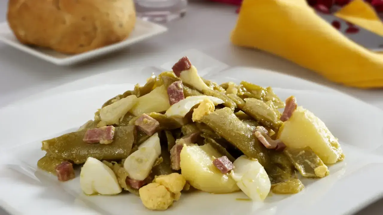 Deliciosa ensalada de judías verdes con trocitos de jamón y huevo duro, acompañada de patatas. Un plato casero y sabroso.