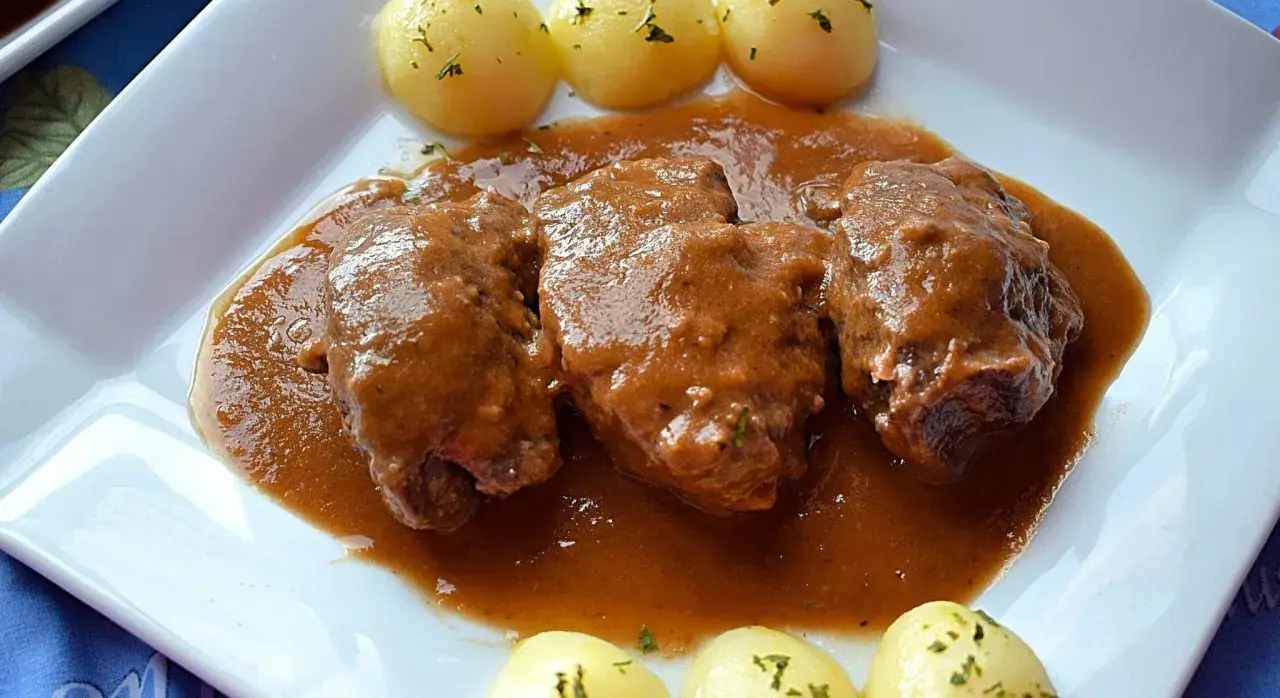 Carrilleras de ternera estofadas en salsa, acompañadas de patatas cocidas y espolvoreadas con perejil. Un plato casero y reconfortante.